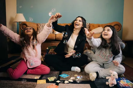 Mariana brincando com bolhas com duas crianças — representando o trabalho em grupo